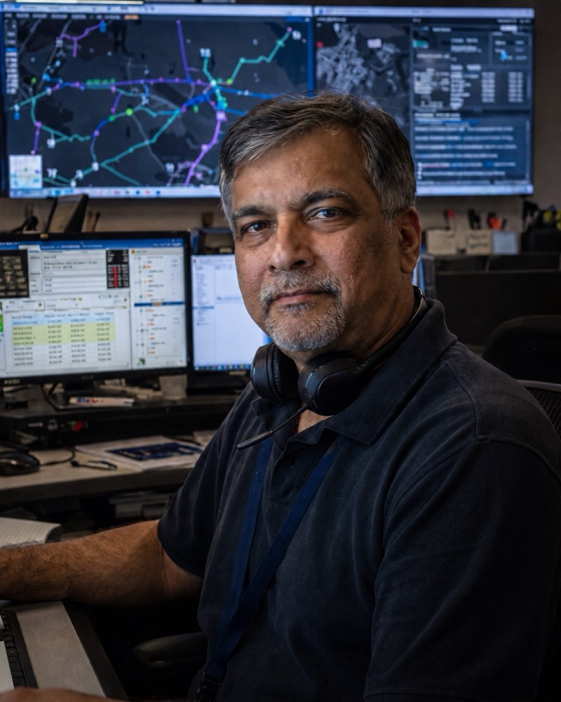Portrait of a dispatcher with a headset around his neck in a dim operations control room