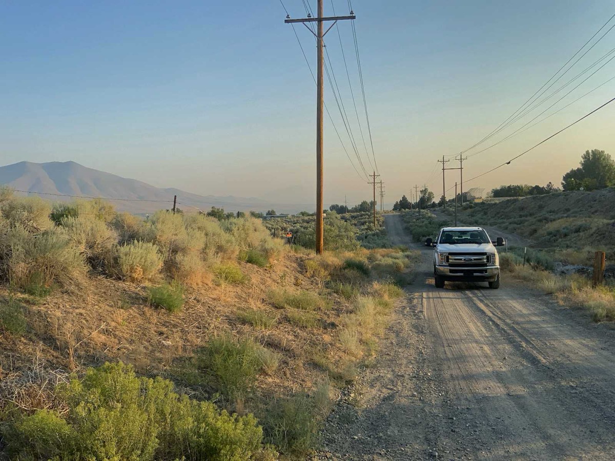 Patrol truck on a high-desert right-of-way road beneath a distribution line in Nevada