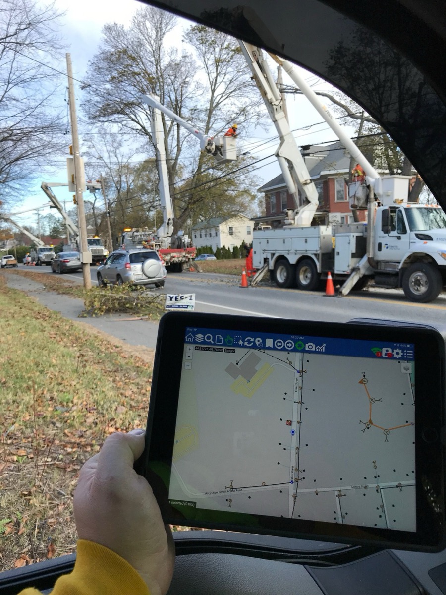 Storm restoration in Maine: a line of bucket trucks working tree-damaged lines along a residential street